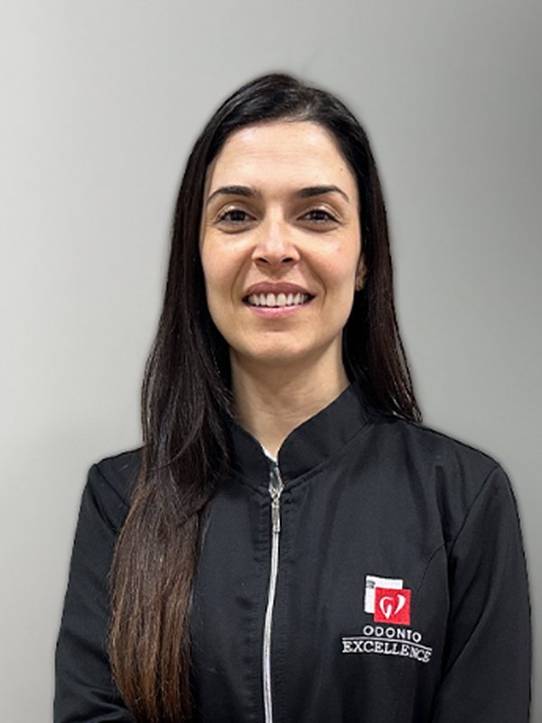 Dra. Bruna Canton, de jaleco preto da clínica, sorrindo